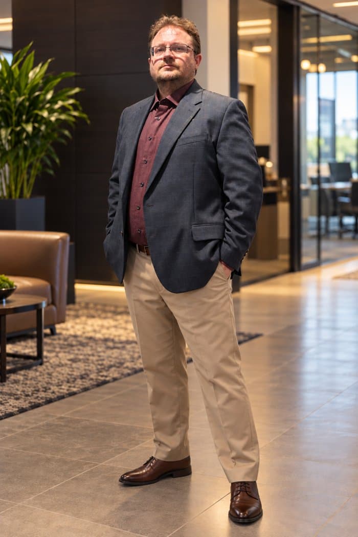 Eric Lemley standing in an office lobby, in a charcoal blazer and khakis